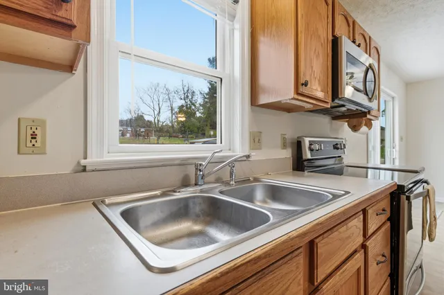 a kitchen with stainless steel appliances granite countertop a sink and a white cabinets next to a window