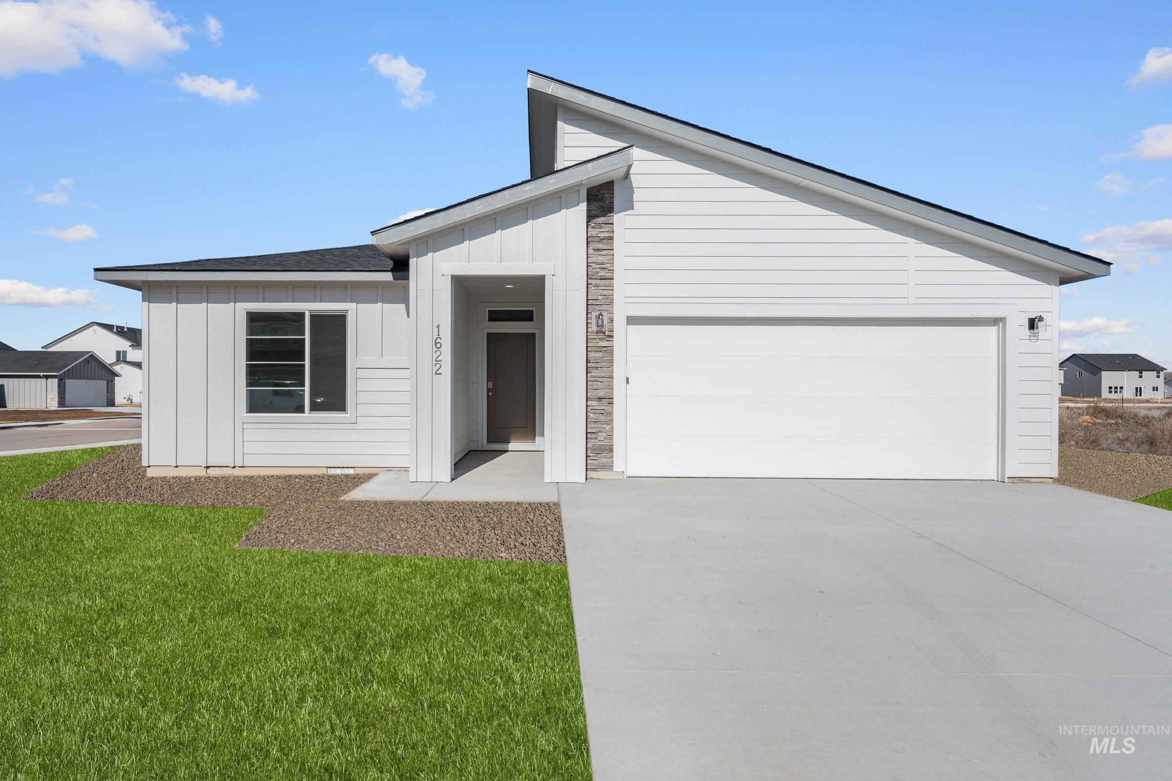 View of front of house featuring an attached garage, board and batten siding, driveway, and a front lawn