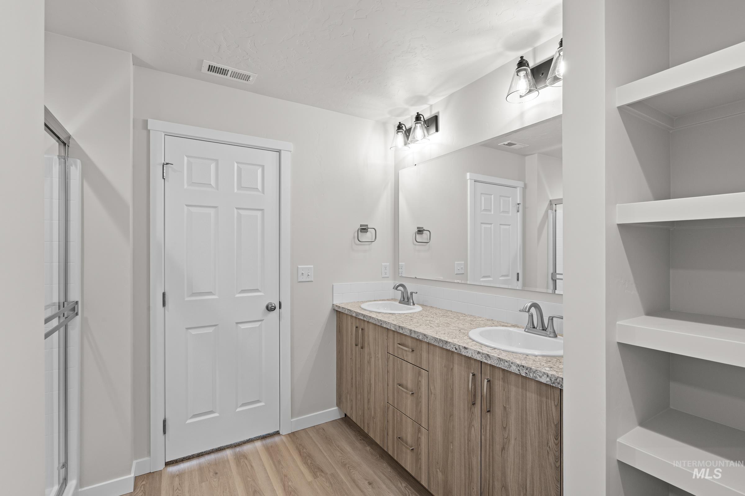 1622 Covington Street Middleton, ID 83644 - Photo 17 of 19 Bathroom with double vanity, light wood-style flooring, and a stall shower