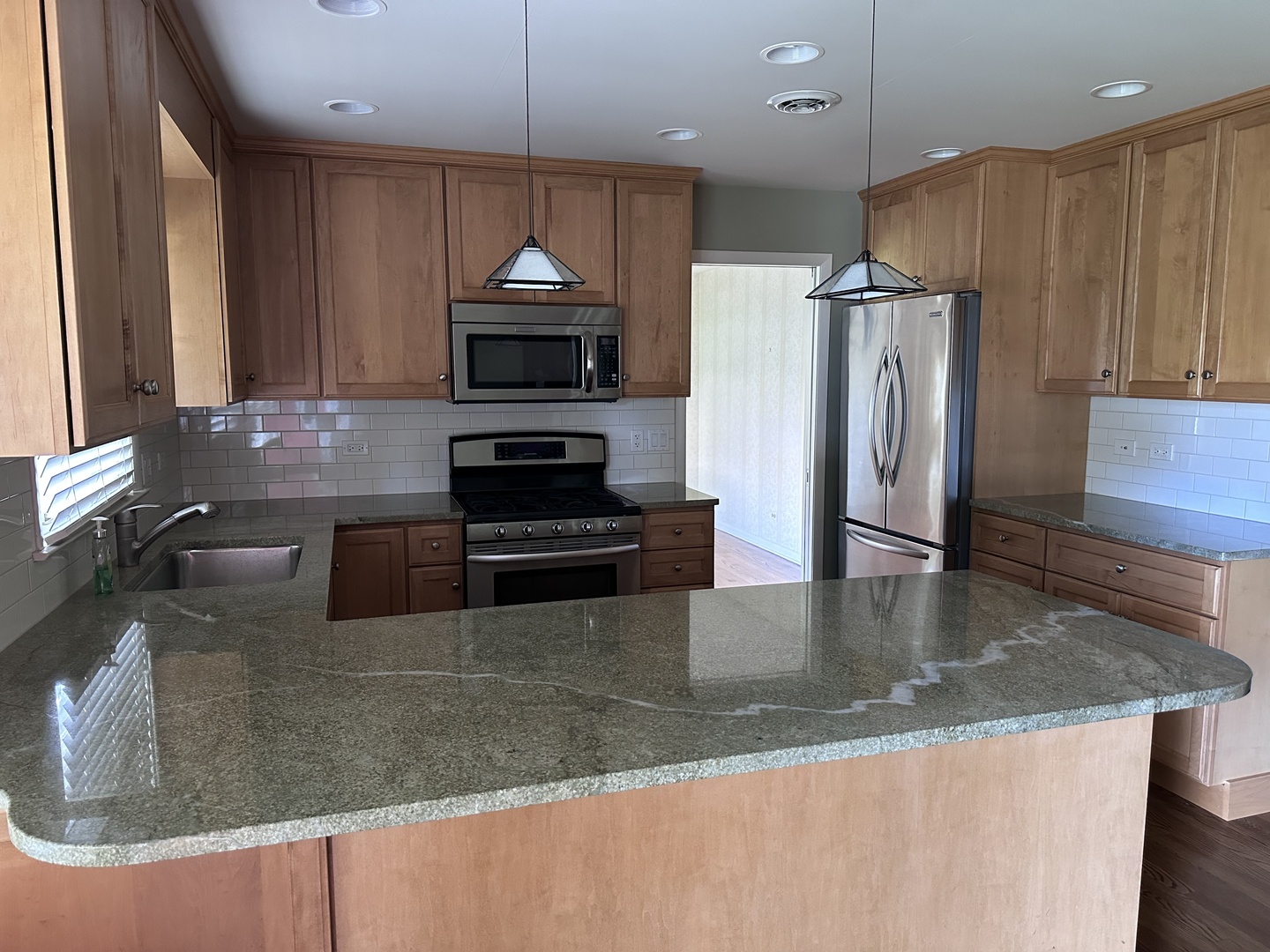 2300 Landwehr Road Northbrook, IL 60062 - Photo 4 of 28 a kitchen with stainless steel appliances granite countertop a sink a stove and a microwave with wooden floor