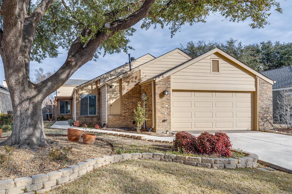 View of front of house with brick siding, driveway, and an attached garage