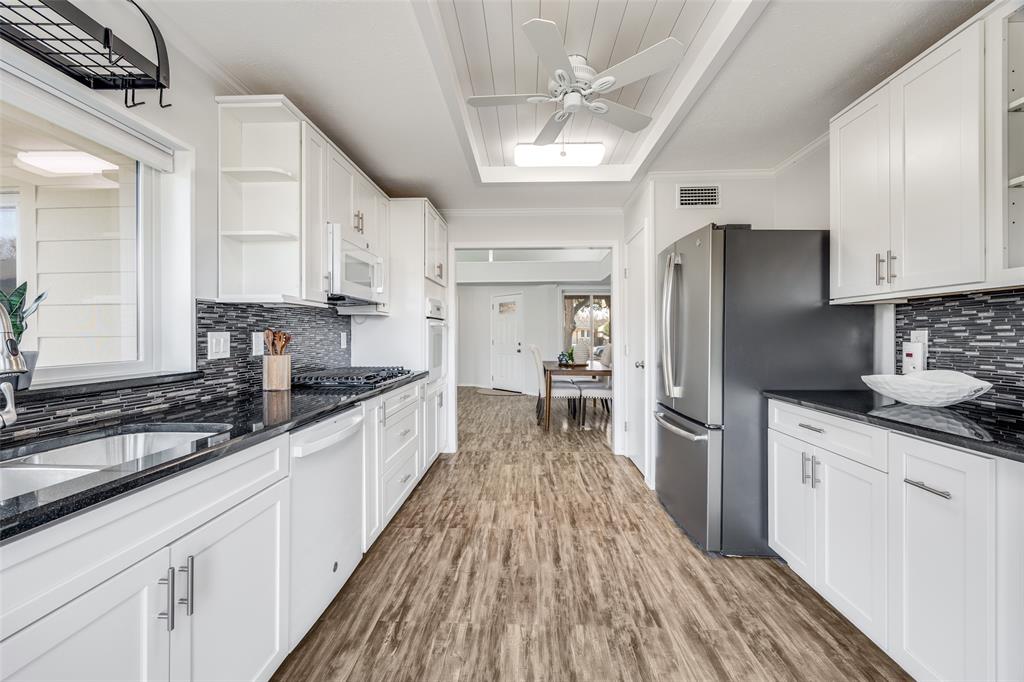 3919 Winter Park Lane Addison, TX 75001 - Photo 12 of 25 Kitchen with tasteful backsplash, open shelves, dark stone counters, white cabinets, and white appliances