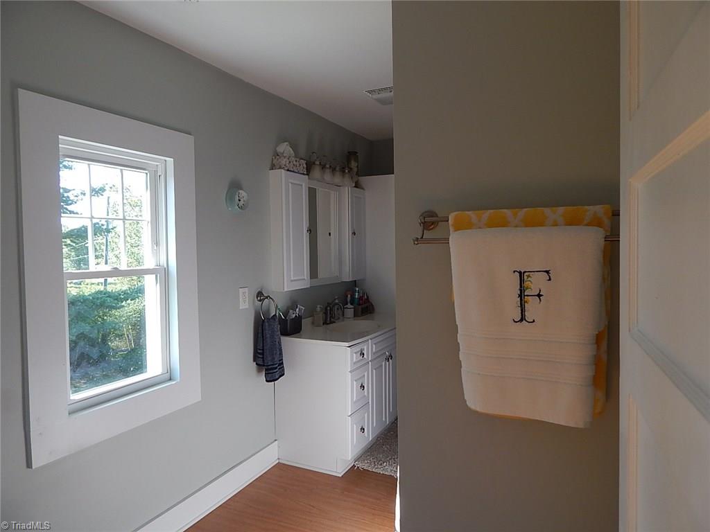 3990 Beasley School Road Sandy Ridge, NC 27046 - Photo 16 of 28 Upstairs bath has wood flooring, white cabinets, and brushed nickel accessories.
