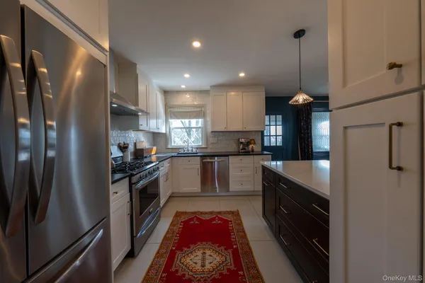 a large kitchen with stainless steel appliances granite countertop a refrigerator and a wooden floor
