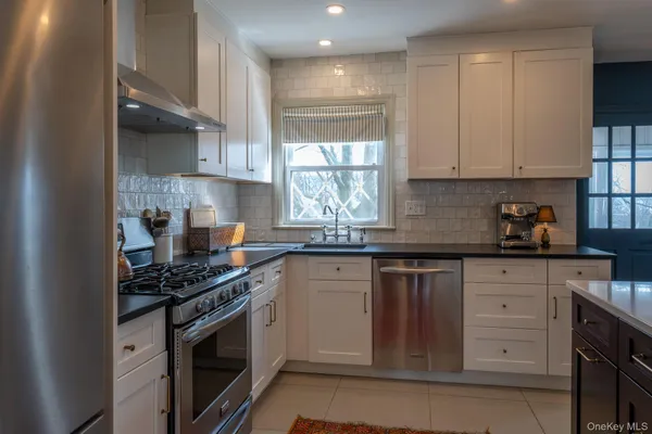 a kitchen with stainless steel appliances granite countertop a stove a sink and a white cabinets