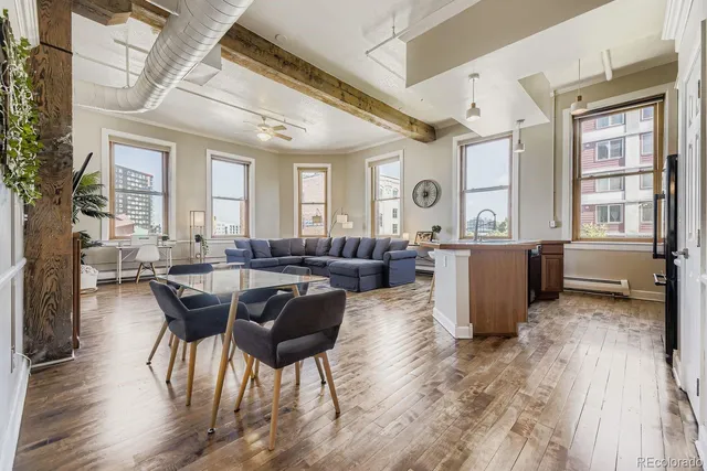 a kitchen with stainless steel appliances granite countertop a refrigerator a sink dishwasher a stove and a dining table with wooden floor