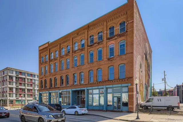 a front view of a building with lot of cars and trees