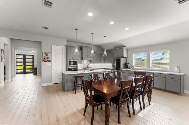 a kitchen with stainless steel appliances a table chairs sink and cabinets