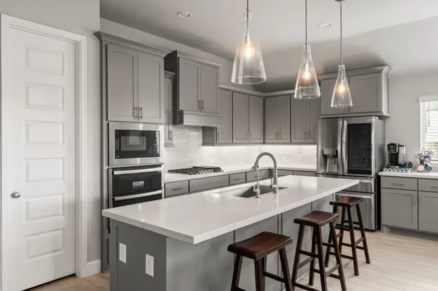 a kitchen with stainless steel appliances a stove a sink a microwave a refrigerator and cabinets