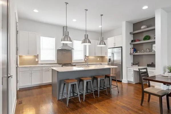 a kitchen with kitchen island granite countertop a table chairs sink and wooden floor