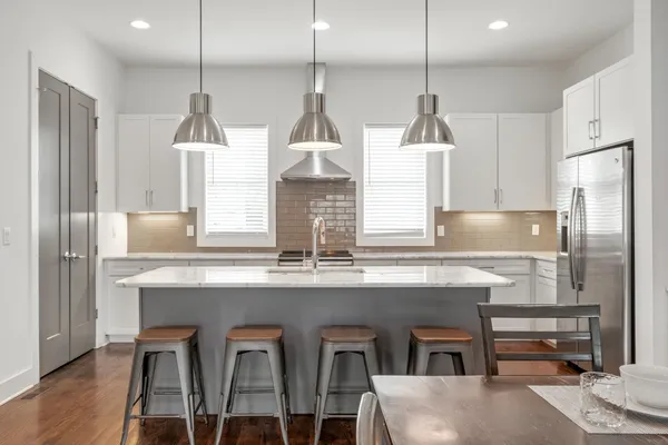 a kitchen with stainless steel appliances granite countertop a sink a stove a refrigerator and island with wooden floor
