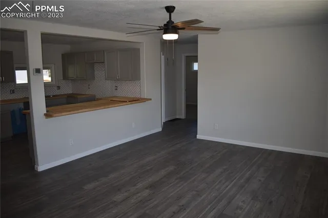 an empty room with wooden floor fan and windows