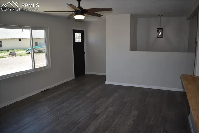 an empty room with wooden floor fan and windows