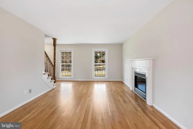 an empty room with wooden floor fireplace and windows