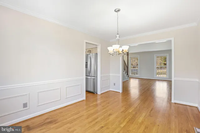 a view of a livingroom with wooden floor a ceiling fan and kitchen space