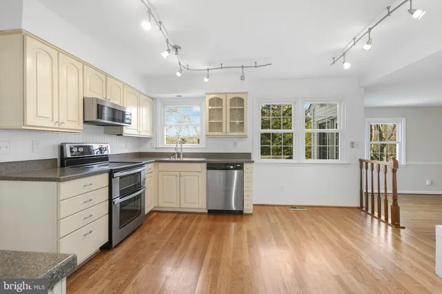 a kitchen with granite countertop a stove top oven a sink dishwasher white cabinets and wooden floor