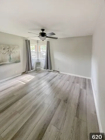 a view of an empty room with a window and wooden floor
