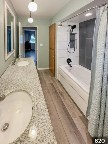 a en suite bathroom with a granite countertop tub shower and mirror