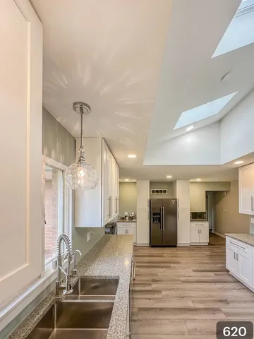 a room with stainless steel appliances kitchen island granite countertop a sink and cabinets