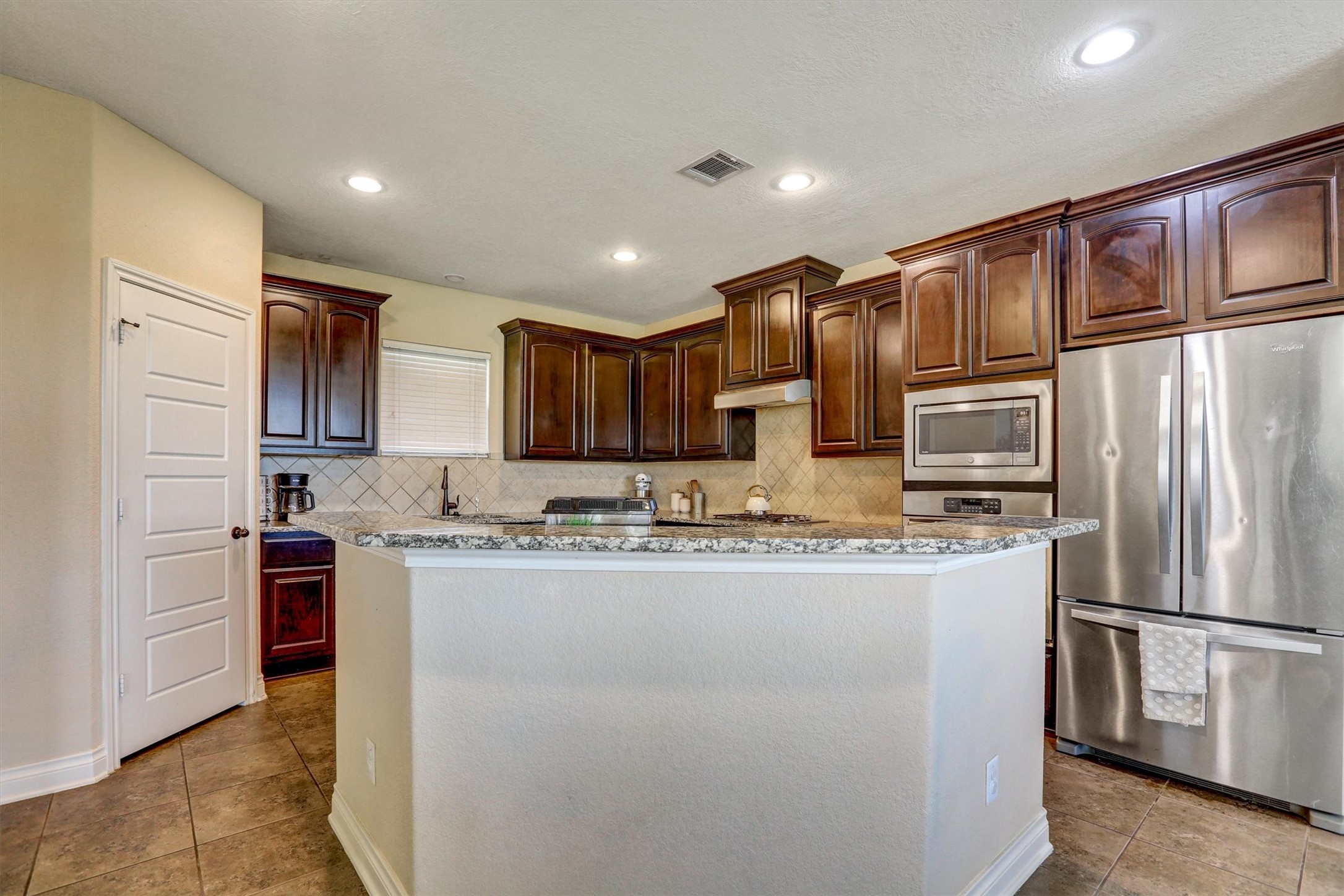 8131 Brinkmeyer Road Needville, TX 77461 - Photo 40 of 49 Spacious kitchen with elegant dark wood cabinetry, stainless steel appliances, and a stylish granite countertop.