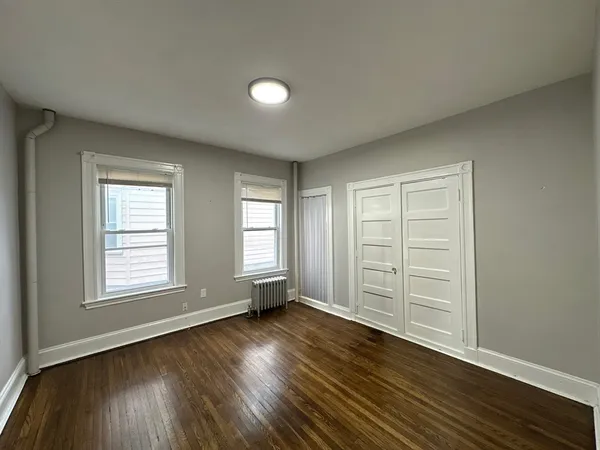 an empty room with wooden floor and window