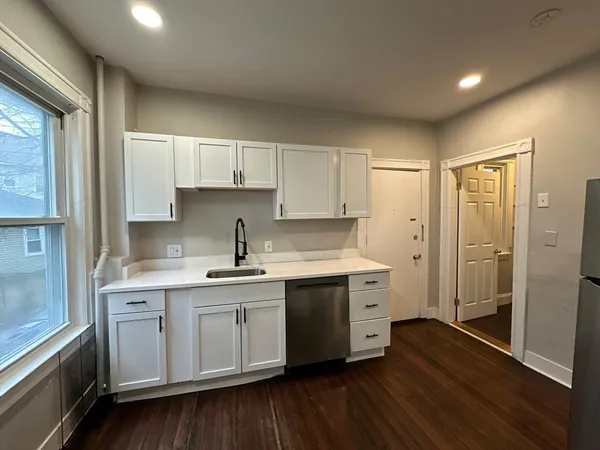 a kitchen with a sink cabinets stainless steel appliances and wooden floor