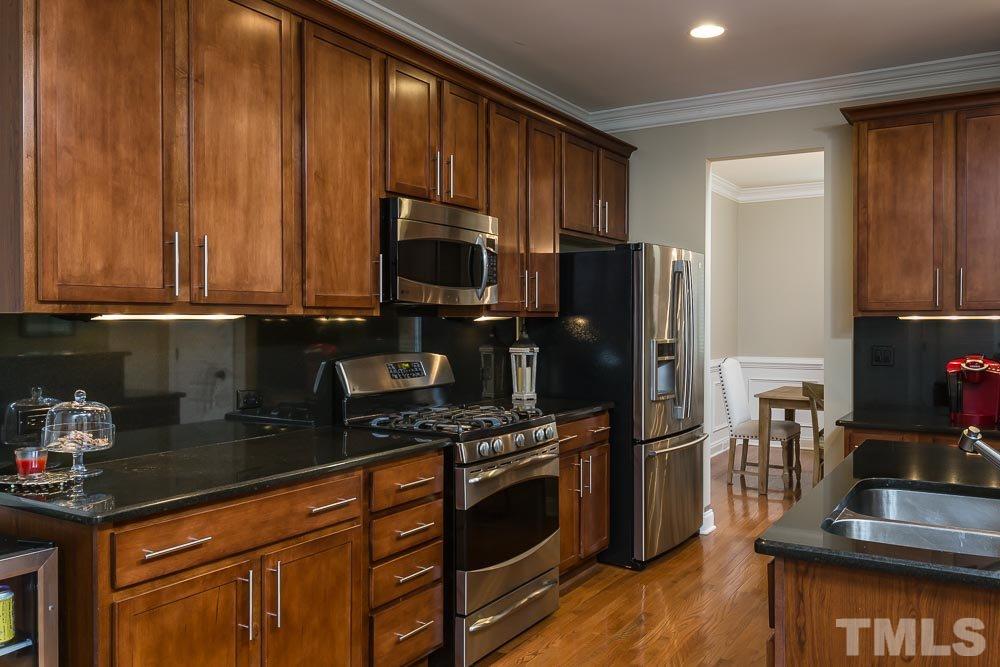 654 Democracy Street Raleigh, NC 27603 - Photo 7 of 24 a kitchen with stainless steel appliances granite countertop a stove a refrigerator and a microwave
