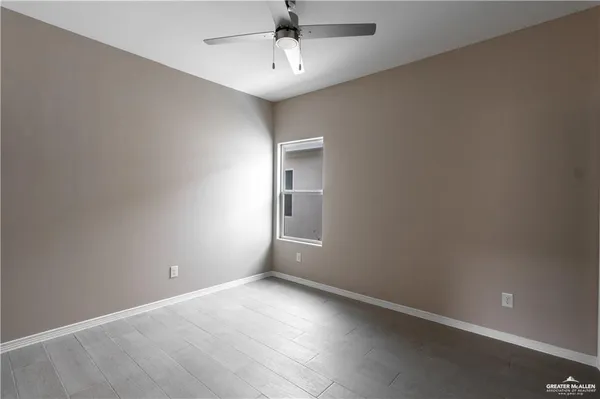 an empty room with a chandelier fan and windows