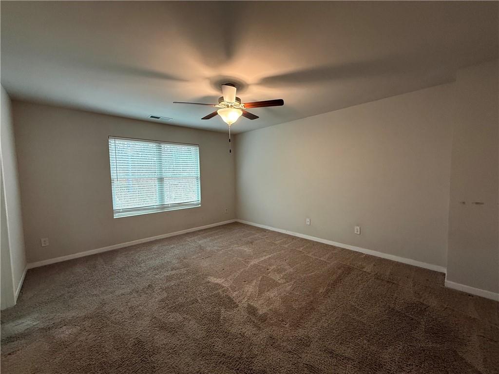 4299 Traipse Path Ellenwood, GA 30294 - Photo 7 of 12 an empty room with a chandelier fan and windows