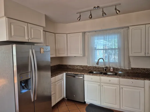a kitchen with white cabinets white stainless steel appliances and sink