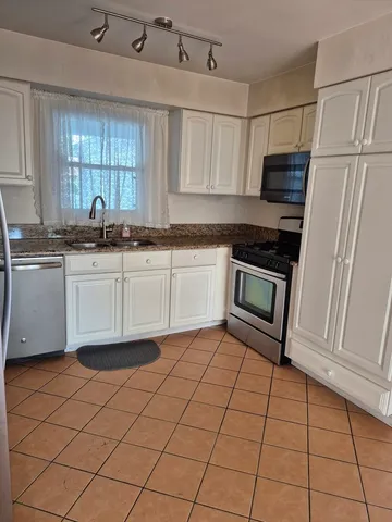 a kitchen with stainless steel appliances granite countertop a sink stove and cabinets