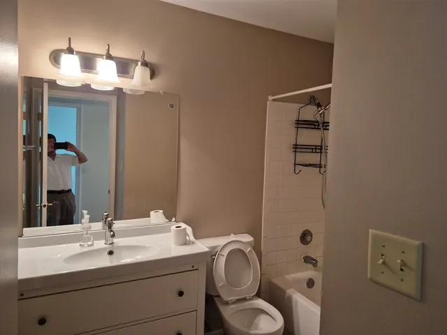 a bathroom with a granite countertop sink toilet and shower