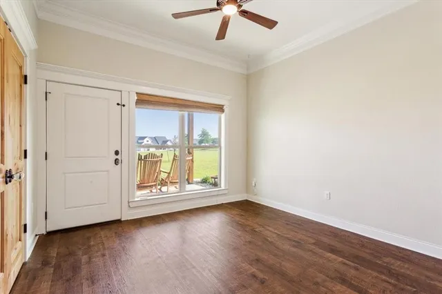 an empty room with wooden floor fan and windows