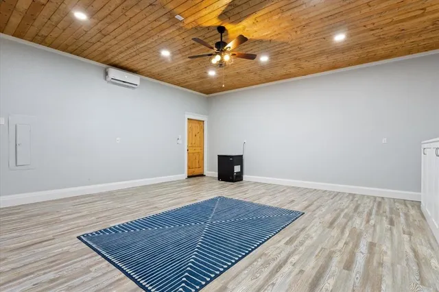 a view of an empty room with wooden floor and a chandelier fan