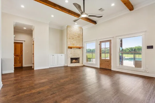 a view of an empty room with a window and wooden floor