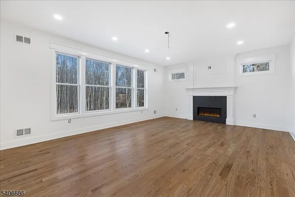 a view of an empty room with wooden floor fireplace and a window