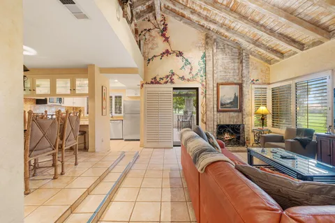 a living room with furniture a fireplace and a floor to ceiling window
