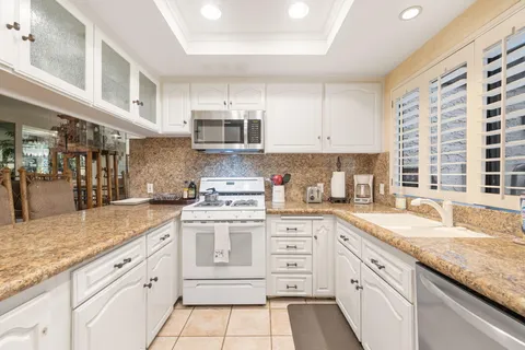 a kitchen with granite countertop white cabinets and white appliances