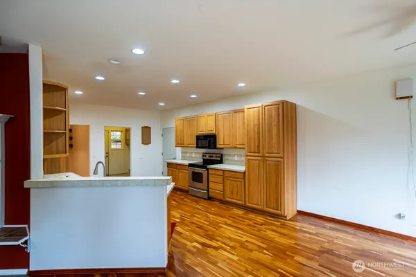 a living room with stainless steel appliances furniture refrigerator and a kitchen counter top