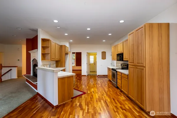 a kitchen with stainless steel appliances kitchen island granite countertop a refrigerator oven a stove top oven with wooden floor