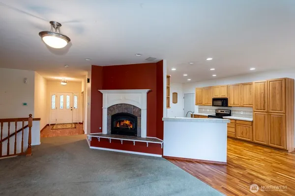 a living room with stainless steel appliances wooden floor and a fireplace