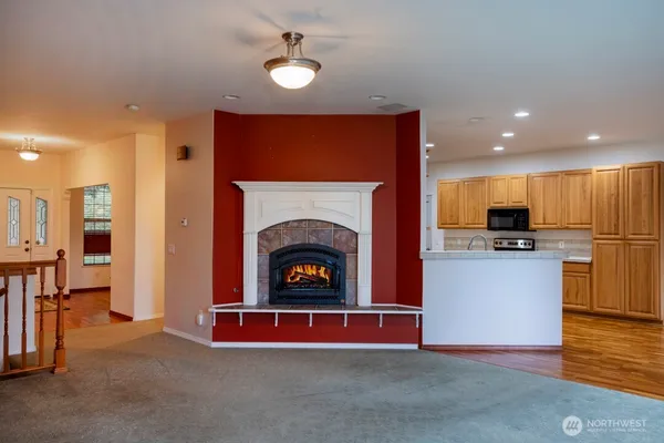 a living room with stainless steel appliances furniture a fireplace and a open kitchen view