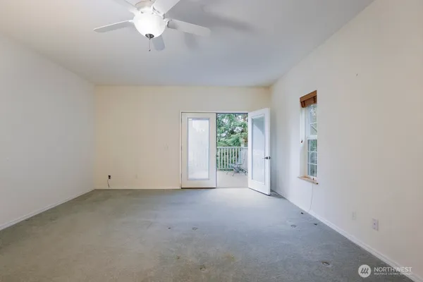an empty room with a chandelier fan and windows