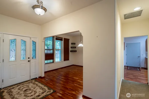 a view of an empty room with a window and wooden floor