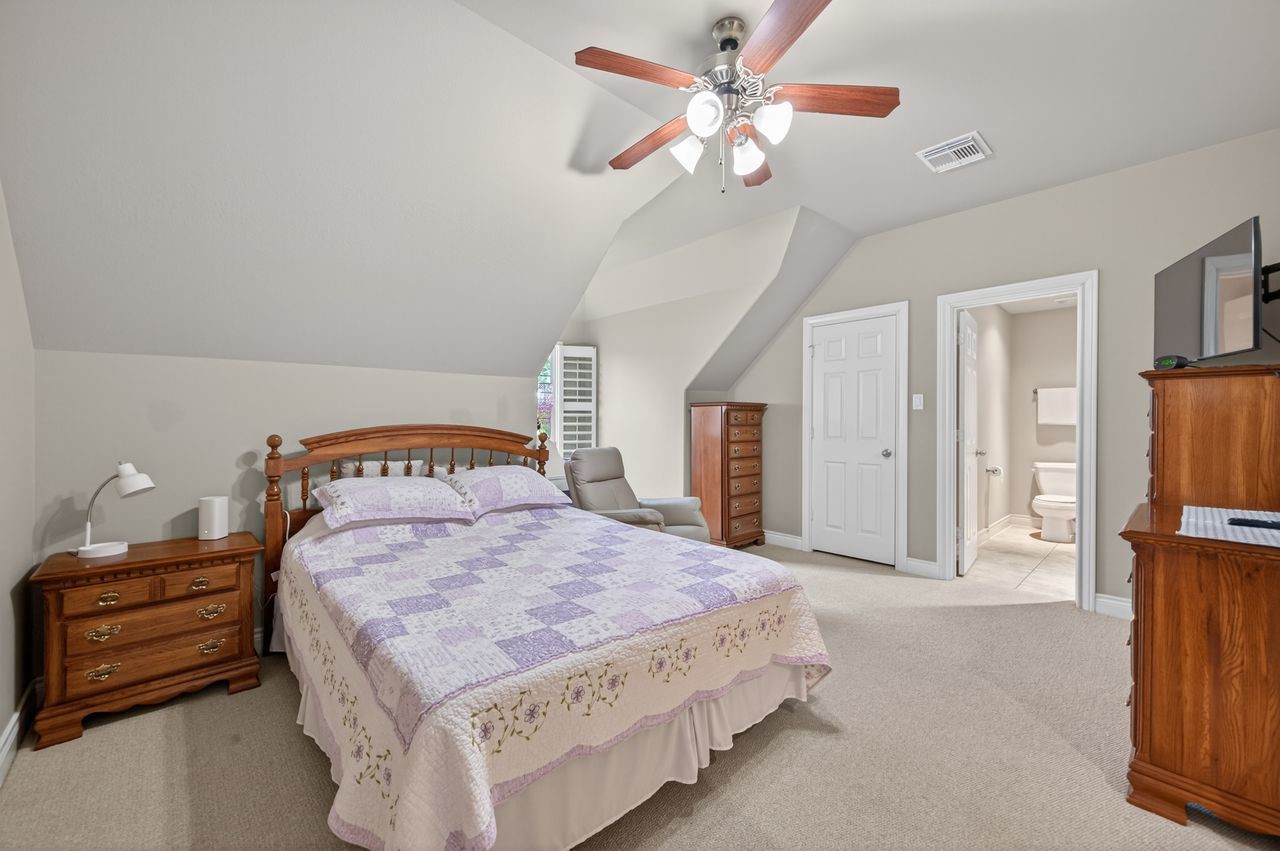 10932 Lasso Lane Houston, TX 77079 - Photo 28 of 38 a bedroom with a bed a dresser and a chandelier