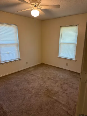 an empty room with a chandelier fan and windows