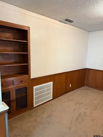 a view of an empty room with cabinet and a window