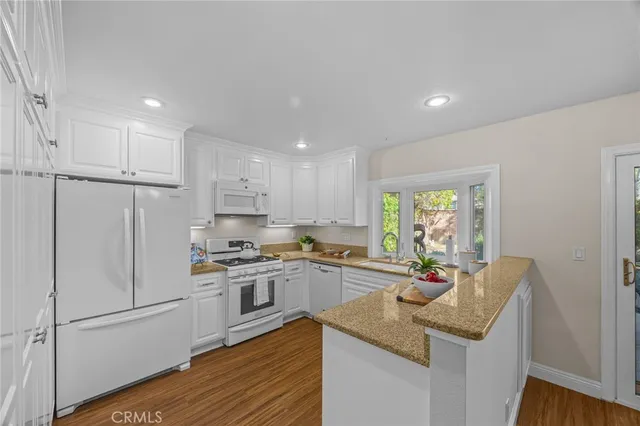 a kitchen with a sink a stove a refrigerator and white cabinets