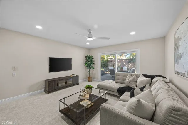 a living room with furniture a flat screen tv and a large window