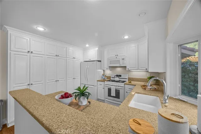 a kitchen with stainless steel appliances granite countertop a sink a stove and a wooden floors